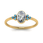 Load image into Gallery viewer, petite-bezel-set-oval-shaped-diamond-engagement-ring-with-blue-topaz-in-yellow-gold-FD9175OVRGICBLTOANGLE5-NL-YG